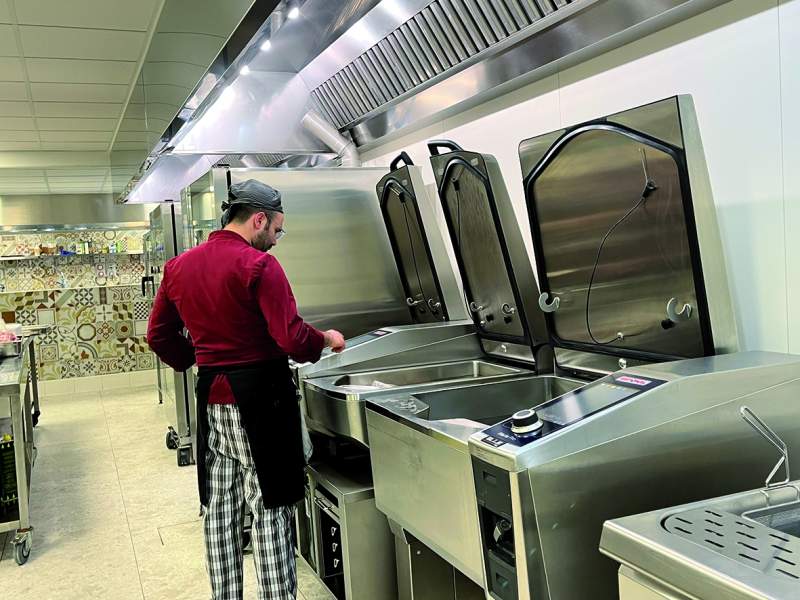 Un cuoco al lavoro nelle cucine UNA Hotel Mh Matera dotate dei sistemi di cottura Rational